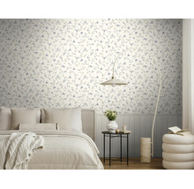 Licht vliesbehang met blauw bloemenpatroon in een moderne slaapkamer met een licht bed, booglamp en bijzettafel.