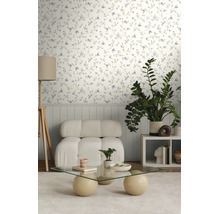 Lichte kamer met behang met delicaat bloemenpatroon, een witte fauteuil en een glazen salontafel.