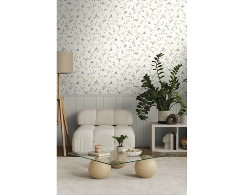 Lichte kamer met behang met delicaat bloemenpatroon, een witte fauteuil en een glazen salontafel.