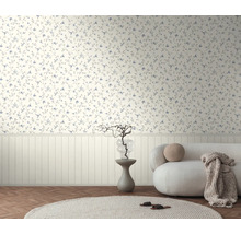 Bloemenbehang met kleine bloemen boven een witte lambrisering in een lichte kamer met een bank en visgraatvloer.