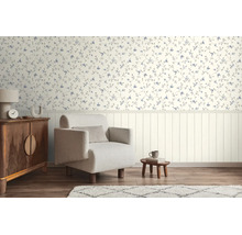 Lichte woonkamer met bloemenbehang boven, verticale wandpanelen beneden, een fauteuil en houten meubels op vloer met houtlook.