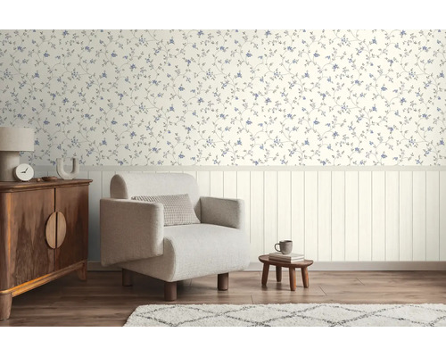 Lichte woonkamer met bloemenbehang boven, verticale wandpanelen beneden, een fauteuil en houten meubels op vloer met houtlook.