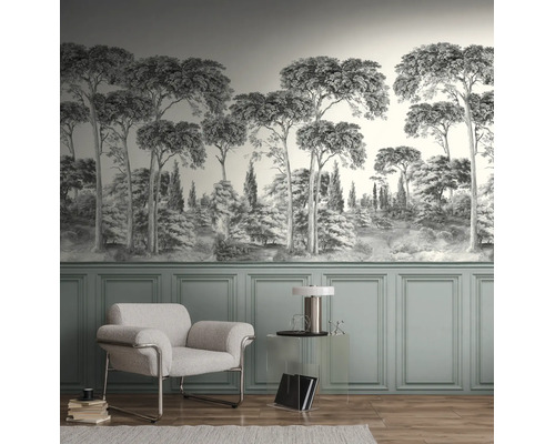 Lichte woonkamer met monochroom fotobehang met boslandschap boven groene lambrisering, een witte fauteuil en een transparante bijzettafel.