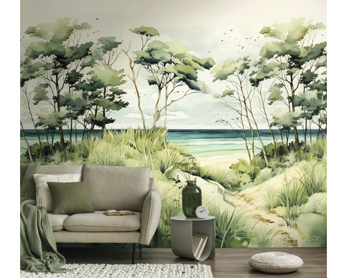 Fotobehang met kustlandschap, duinen, bomen en zee in aquarelstijl achter een lichtgrijze bank in een woonkamer.