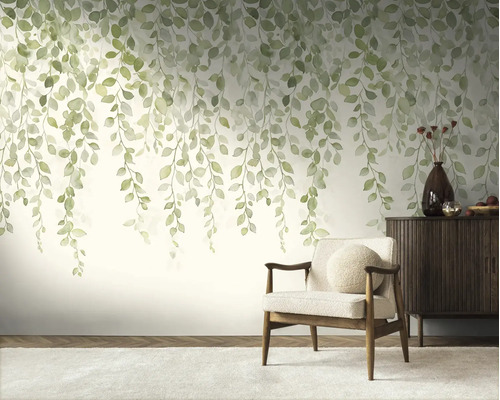 Fotobehang met hangende groene bladeren in aquarelstijl in een licht ingerichte woonkamer met fauteuil en dressoir.