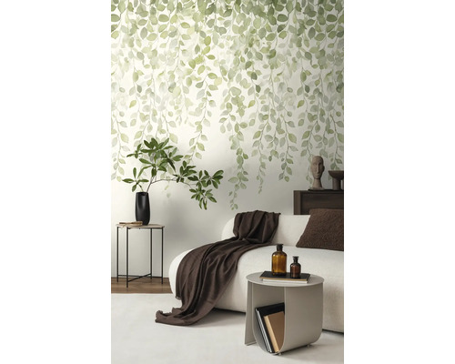 Vliesbehang met hangend bladmotief in aquarelstijl in een modern ingerichte woonkamer met bank en bijzet tafel.