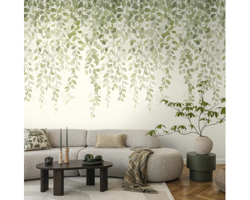 Fotobehang met hangende groene bladeren in aquarelstijl in een lichte woonkamer met grijze bank.