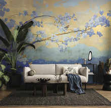 Fotobehang met artistiek bloesemtakmotief in een moderne woonkamer met een lichte bank, donker vloerkleed en grote kamerplanten.