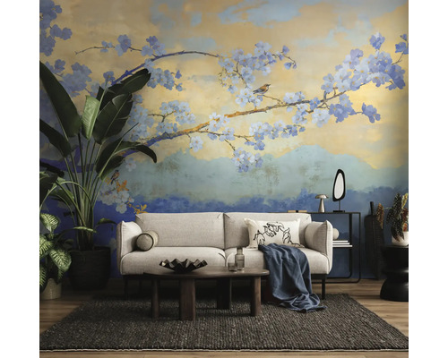 Fotobehang met artistiek bloesemtakmotief in een moderne woonkamer met een lichte bank, donker vloerkleed en grote kamerplanten.