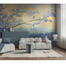 Vliesbehang met bloesemtak en vogel in een moderne woonkamer met een witte modulaire bank en blauw wandpaneel.