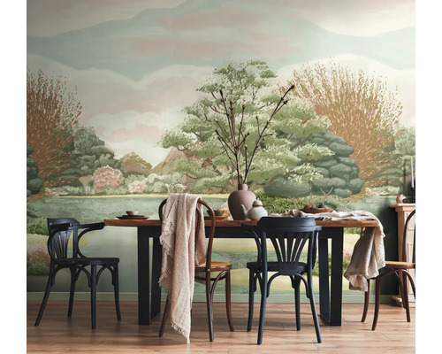 Fotobehang met geschilderd landschap van heuvels, bomen en een meer in een eetkamer met houten tafel en stoelen.