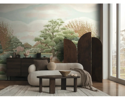 Lichte woonkamer met fotobehang met landschapsmotief, een witte bank, een donkere salontafel en een boogvormig houten kamerscherm.