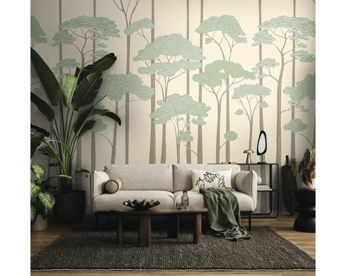 Woonkamer met fotobehang met boommotief, lichtgrijze bank, donkere houten tafel, geweven tapijt en grote kamerplanten.