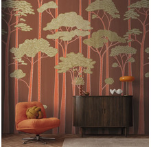 Vliesbehang met gestileerd bosmotief in retrostijl, gecombineerd met een houten dressoir, een fauteuil en woonaccessoires.