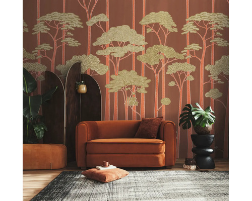 Vliesbehang met bosmotief in een woonkamer met oranje fauteuil, donker kamerscherm, kamerplanten en een tapijt met patroon.