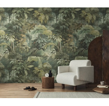Vliesbehang met jungle-motief en groene bladeren in een modern ingerichte woonkamer met een witte fauteuil en houten vloer.