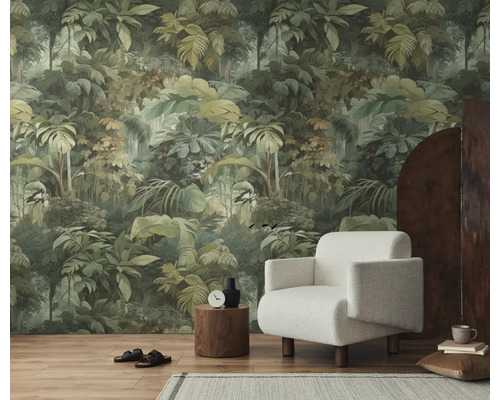 Vliesbehang met jungle-motief en groene bladeren in een modern ingerichte woonkamer met een witte fauteuil en houten vloer.