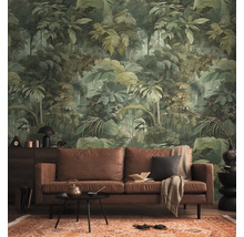Vliesbehang met jungle-motief en tropische bladeren in een woonkamer met een bruine leren bank en een gedessineerd tapijt.
