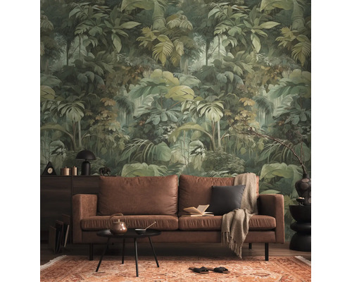Vliesbehang met jungle-motief en tropische bladeren in een woonkamer met een bruine leren bank en een gedessineerd tapijt.