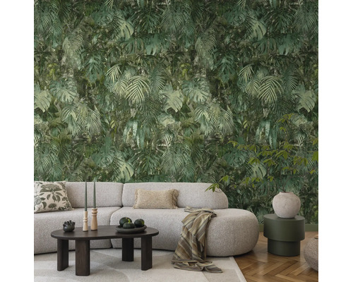 Vliesbehang met jungle-motief, monstera- en palmbladeren in een modern ingerichte woonkamer met geweven bank en houten tafel.