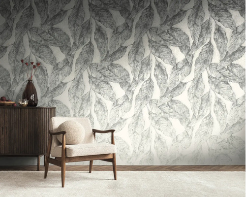 Lichte woonkamer met een groot fotobehang met bladerdessin, een houten fauteuil met stoffen bekleding en een donker houten dressoir.
