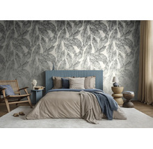 Moderne slaapkamer met behang met groot bladmotief, een blauw gestoffeerd bed en diverse houten meubels in aardetinten.
