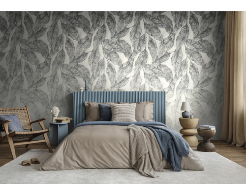 Moderne slaapkamer met behang met groot bladmotief, een blauw gestoffeerd bed en diverse houten meubels in aardetinten.