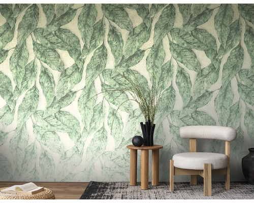 Lichte woonkamer met botanisch fotobehang met groot bladpatroon, moderne fauteuil, houten bijzettafel en decoratieve elementen.