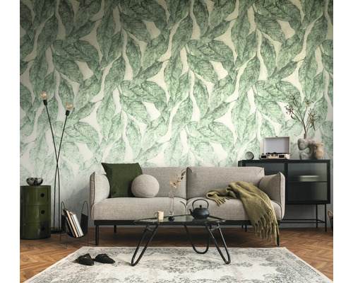 Vliesbehang met bladpatroon in een modern ingerichte woonkamer met bank, salontafel en visgraatparket.