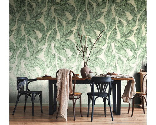 Licht ingerichte eetkamer met behang in botanisch bladontwerp, een houten tafel met zwarte poten en diverse houten stoelen.