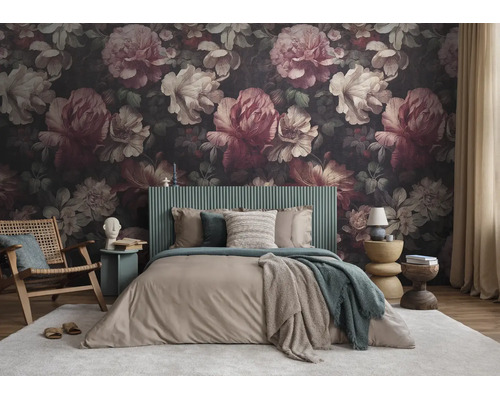 Vliesbehang met een groot bloemenpatroon in een slaapkamer met een groen hoofdbord en houten stoel.