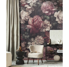 Woonkamer met donker fotobehang met groot bloemenpatroon, witte fauteuil en zwarte meubels.