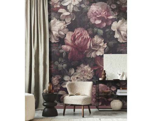 Woonkamer met donker fotobehang met groot bloemenpatroon, witte fauteuil en zwarte meubels.