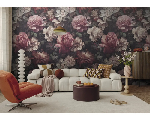 Woonkamer met donker bloemenbehang, witte bank, oranje fauteuil, ronde salontafel en licht tapijt in een modern ontwerp.