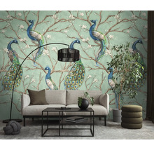 Lichte woonkamer met decoratief behang met pauwen op bloesemtakken, bank, salontafel en booglamp.