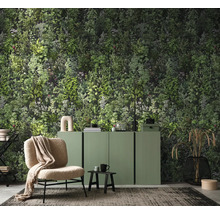Fotobehang met dicht botanisch bladpatroon in een woonkamer met een groen dressoir en fauteuil.