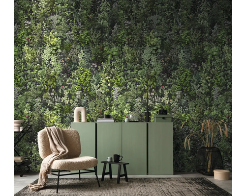 Fotobehang met dicht botanisch bladpatroon in een woonkamer met een groen dressoir en fauteuil.