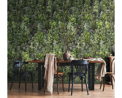 Eetkamer met botanisch behang met een dicht groen blader- en plantenpatroon voor een houten eettafel met stoelen.