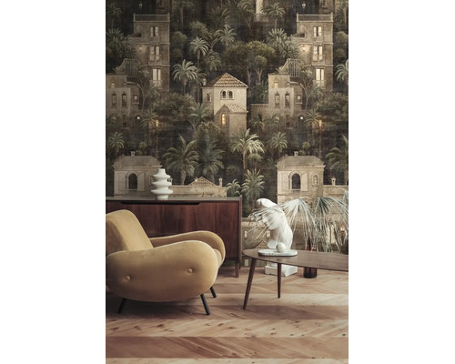 Woonkamer met donker fotobehang met huis- en palmboommotief, beige fauteuil, houten meubels en parketvloer.