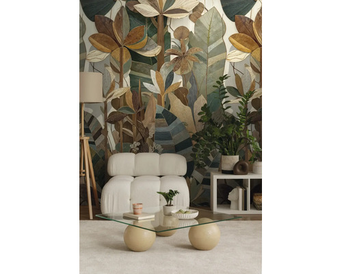 Vliesbehang met botanisch patroon van gestileerde bladeren in een moderne woonkamer met fauteuil en glazen salontafel.
