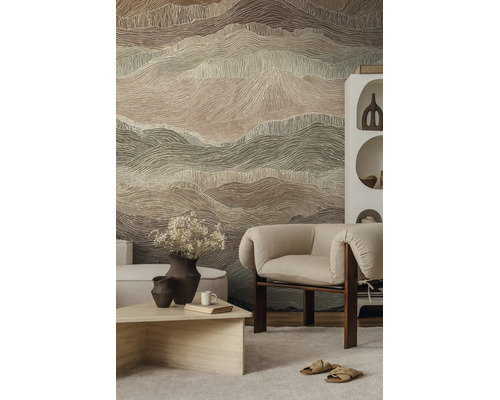 Vliesbehang met abstract golvend patroon in berglook in een modern ingerichte woonkamer met fauteuil en lichte salontafel.