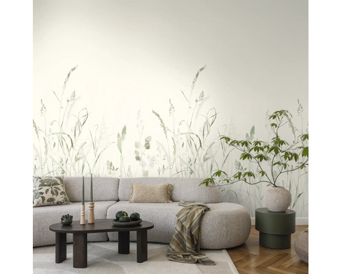 Moderne woonkamer met fotobehang met grasprint, een lichtgrijze bank, donkere salontafel en parketvloer.