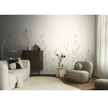 Modern ingerichte woonkamer met fotobehang met grassenmotief, een bank en fauteuil van bouclé-stof en een dressoir van hout.