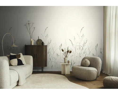 Modern ingerichte woonkamer met fotobehang met grassenmotief, een bank en fauteuil van bouclé-stof en een dressoir van hout.