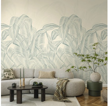 Vliesbehang met groot palmbladpatroon in een licht ingerichte woonkamer met een grijze bank en salontafel.