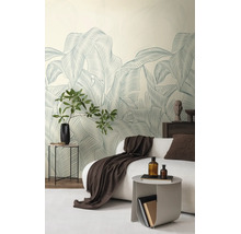 Vliesbehang met groot bladerpatroon in een modern ingerichte woonkamer met een witte bank en decoratie.