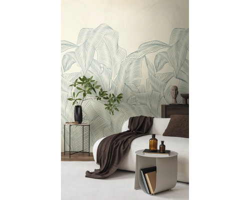 Vliesbehang met groot bladerpatroon in een modern ingerichte woonkamer met een witte bank en decoratie.