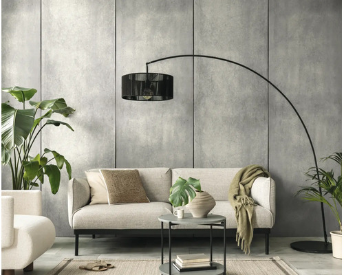 Moderne woonkamer met lichte bank, zwarte booglamp, ronde bijzettafel en kamerplanten voor een muur in betonlook.