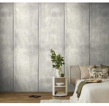 Modern slaapkamerinterieur met grootformaat wandpanelen in grijze betonlook, lichte houten vloer en een wit nachtkastje.