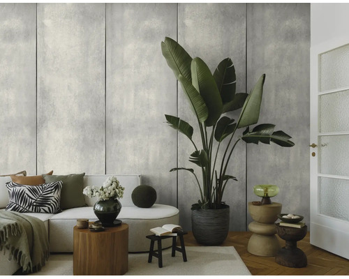 Fotobehang met betonlook in een woonkamer met een witte bank en een grote kamerplant.